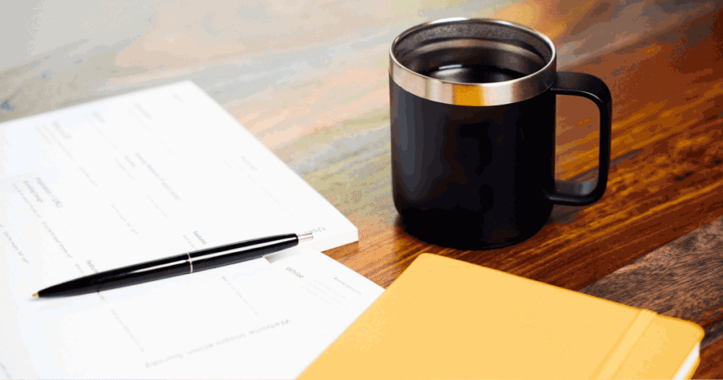 Immigration forms and documents on desk with pen and coffee, representing K-1 visa requirements checklist and application preparation