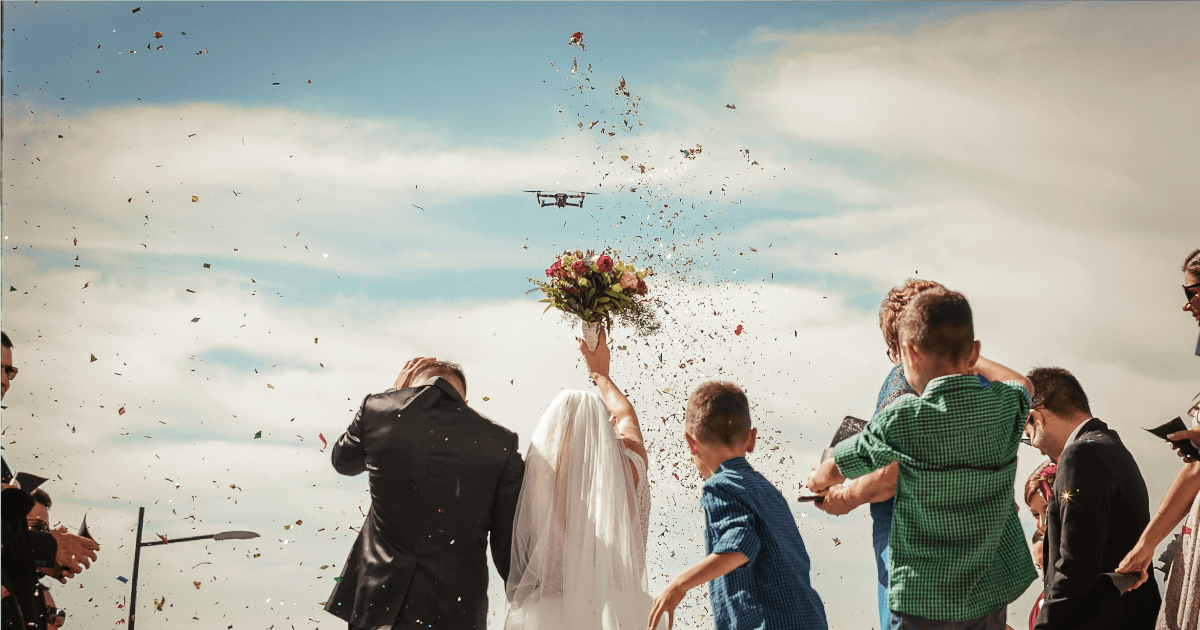 Newlywed couple celebrating with confetti after wedding ceremony under blue sky - beginning their adjustment of status journey together